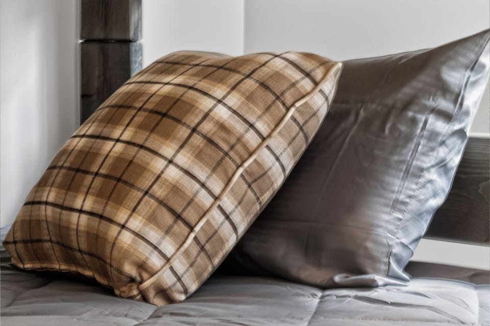 Sink into plush pillows with cozy plaid and silky textures that invite restful nights in your comfortable bedroom retreat.