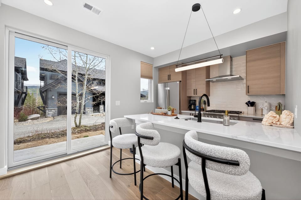 Your sleek kitchen features modern appliances and a breakfast island where you can enjoy coffee while natural light streams through sliding doors.