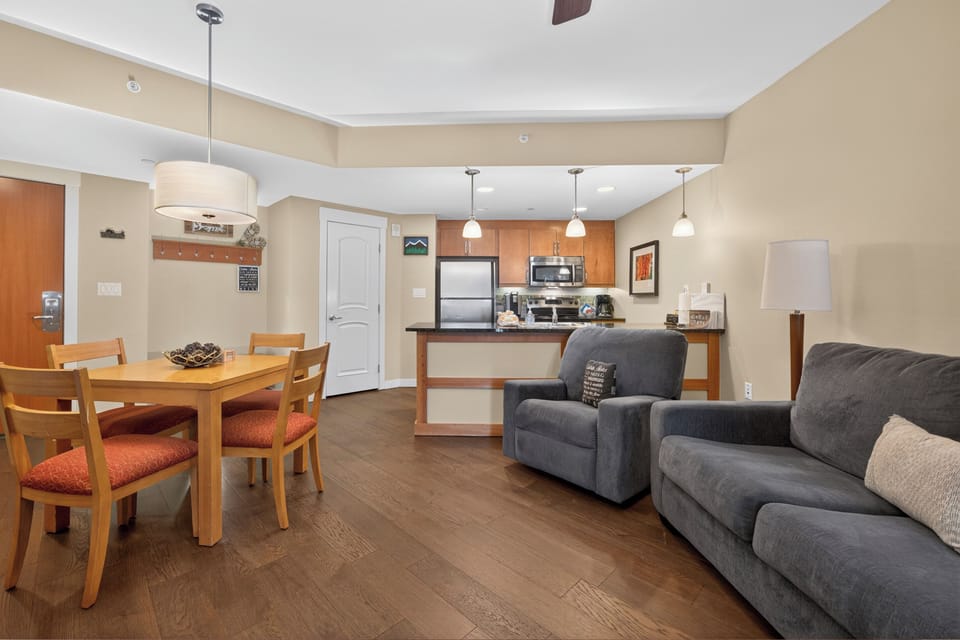 Your inviting open-concept space flows from cozy living area to dining table and fully-equipped kitchen, all bathed in warm lighting and ready for relaxing meals and easy entertaining.