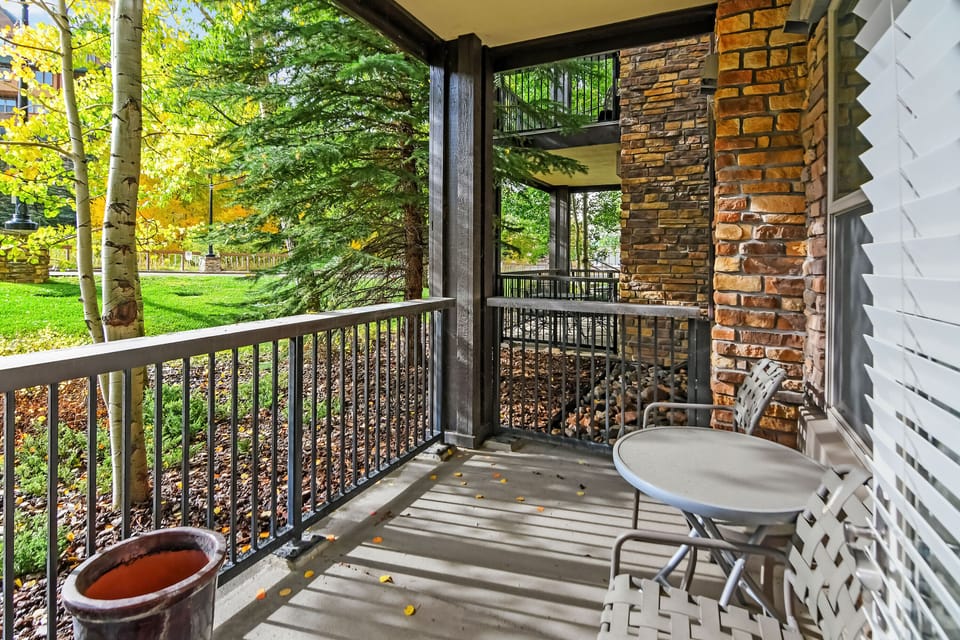 Step onto your private balcony with cozy seating, framed by lush autumn trees and stone accents—your perfect spot to sip morning coffee or unwind with peaceful woodland views.