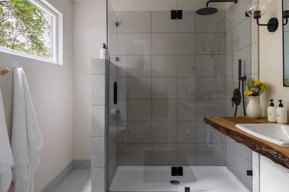 Walk-in shower with custom glass and tile, rainfall shower head, and a solid live edge bathroom vanity. No detail was an afterthought.