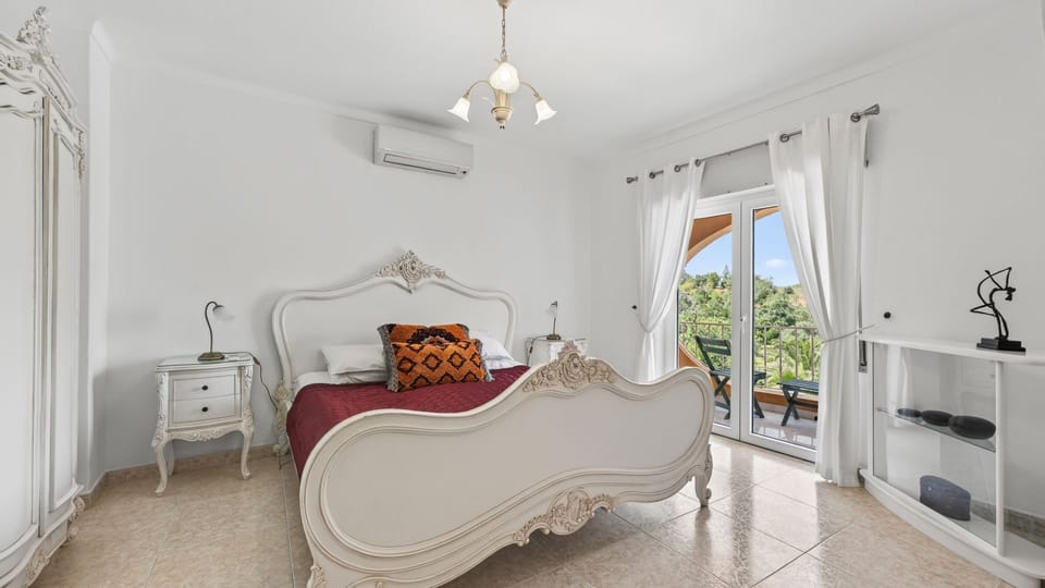 Elegant bedroom with balcony views, AC and soft natural light for restful Algarve nights. #VillaBedroom #AlgarveEscape #PremiumStay