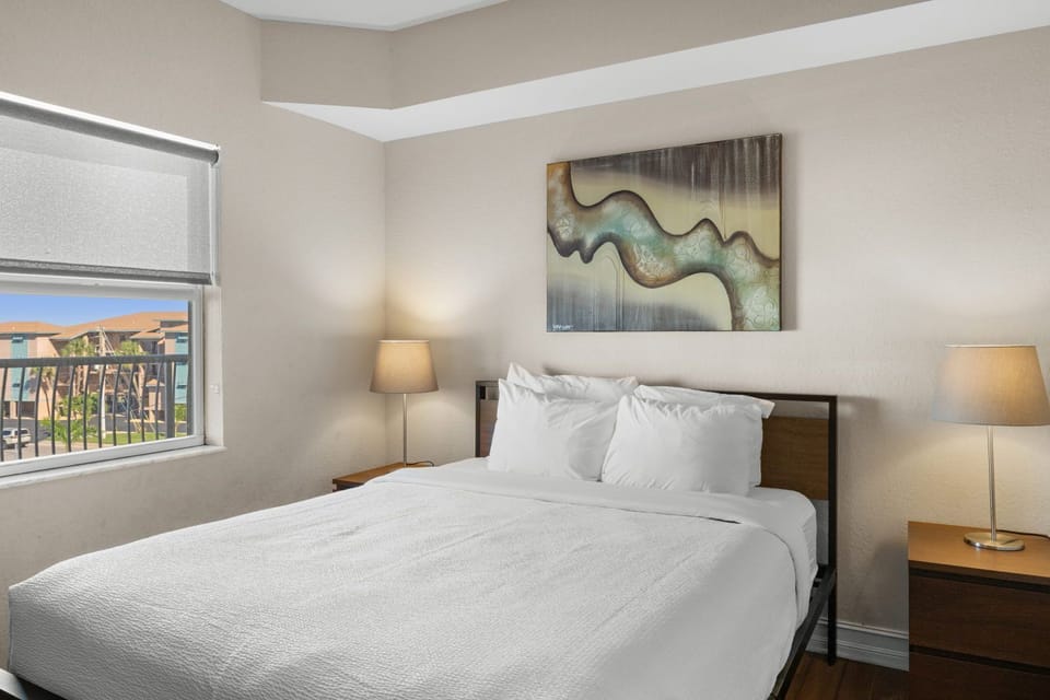 The queen bedroom features vibrant artwork, a wall-mounted TV, and air conditioning for a cool night's sleep.