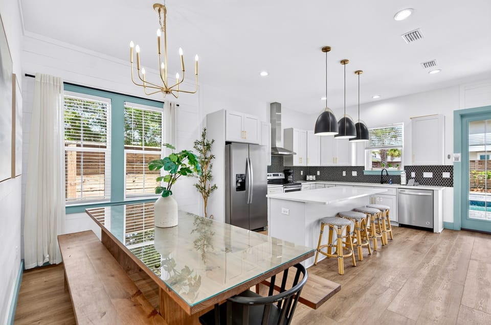 1st floor- Open-concept gourmet kitchen and dining area with glass-top farmhouse table, bench seating, stainless steel appliances, kitchen island with bar stools,—fully equipped for large group meals