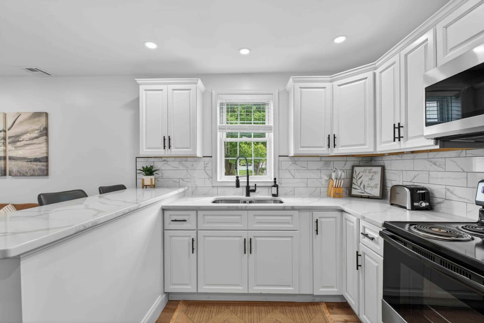 Bright U-shaped kitchen with quartz counters, bar seating, and window view