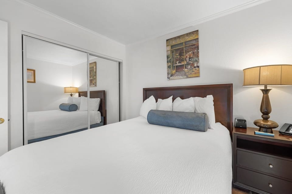 Unwind in a stylish bedroom with mirrors that reflect light and cozy bedding.