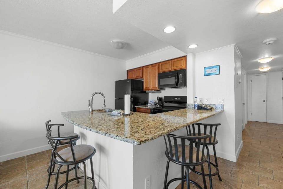 Gather around the breakfast bar, where sleek seating and a stylish kitchen create a welcoming social space.