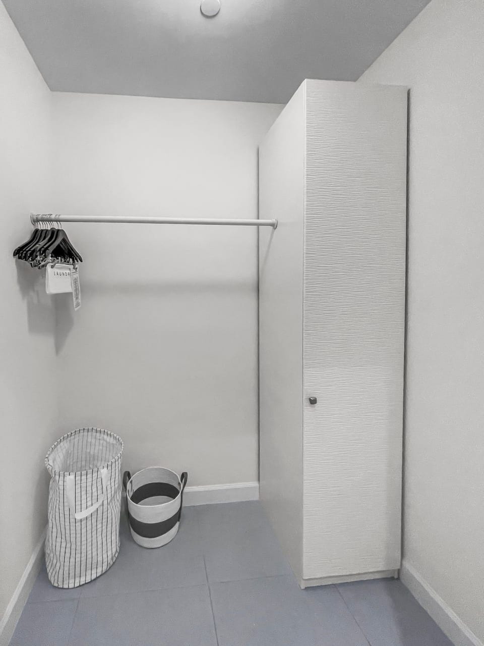 Find practical storage in this organized closet, complete with hangers and laundry baskets.