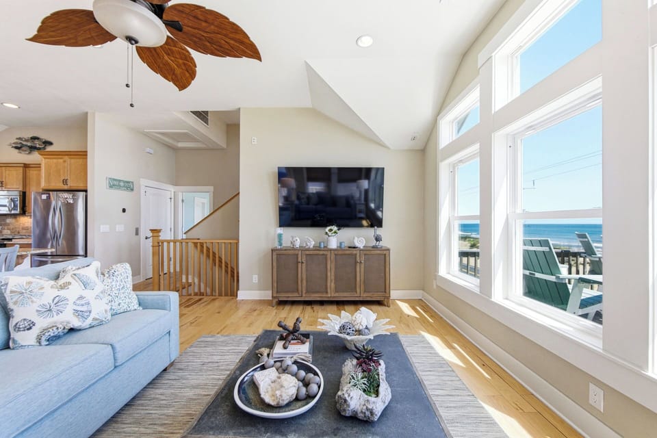 Sun-filled coastal living room with ocean views and a large TV