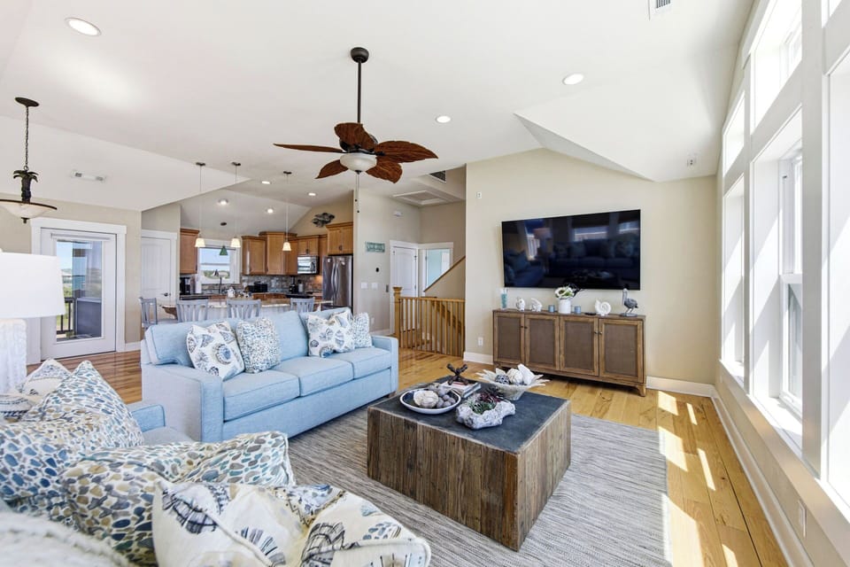 Bright open living room with vaulted ceilings, big windows, and cozy seating
