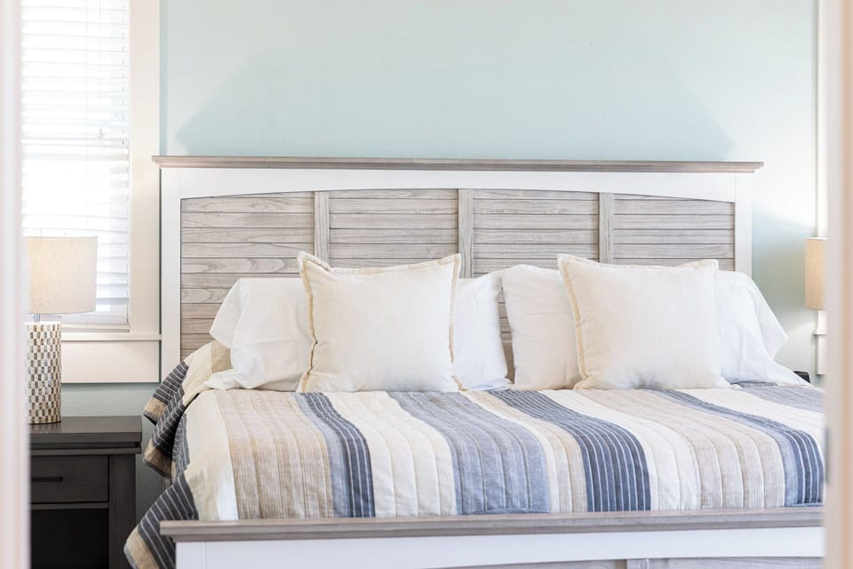 Bright coastal-style bedroom with plush king bed and calming blue accents
