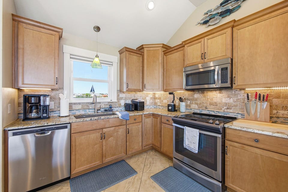 Bright kitchen with granite counters, stainless appliances, and warm wood cabinetry