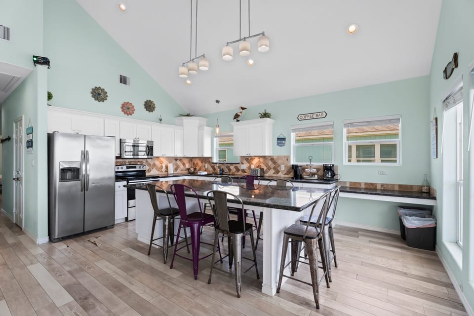 Modern kitchen and dining area with spacious countertops, pendant lighting, bar seating, and open layout for entertaining guests.
