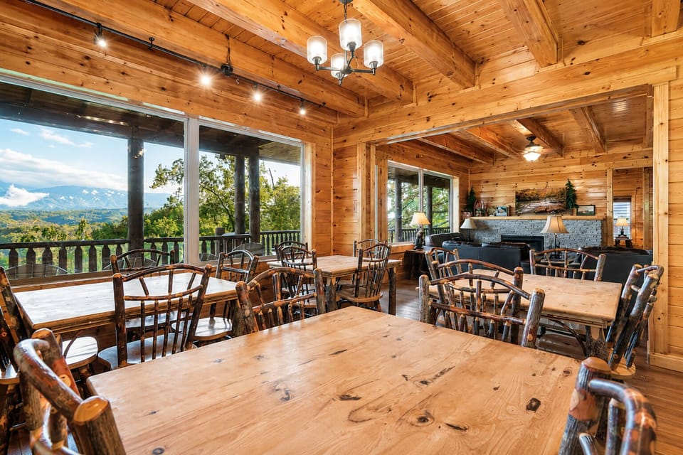 Spacious dining area with long farmhouse tables, panoramic mountain views, and open-air cabin design ideal for group dining and family gatherings.