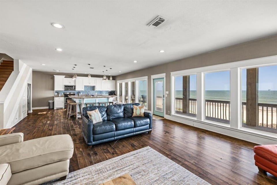 Open-concept beachfront interior with wall-to-wall windows, natural lighting, and direct balcony access overlooking the Gulf.