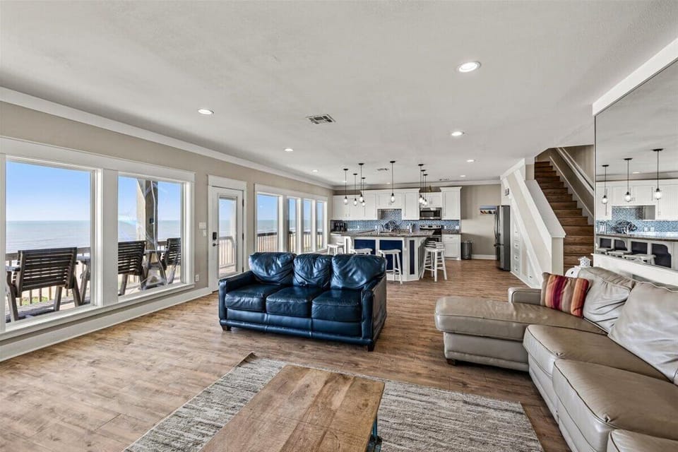 Large open living space with comfortable seating, wood flooring and panoramic beachfront windows. Ideal family gathering room for relaxing after beach days.