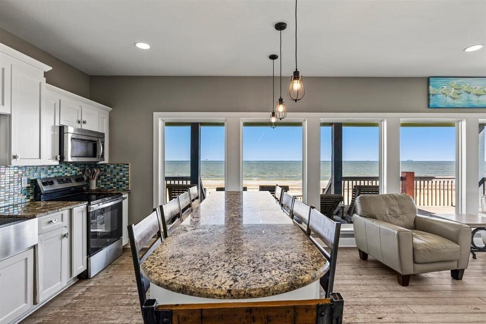 Open dining and living space with breathtaking Gulf views, modern coastal design, and easy access to the beachfront deck for indoor-outdoor entertaining.