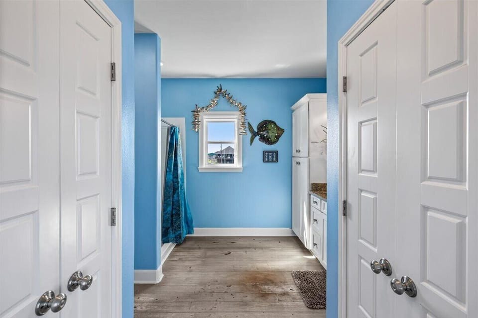 Hallway and bedroom entry area with coastal blue walls, modern finishes, and spacious layout leading to comfortable beachfront accommodations.