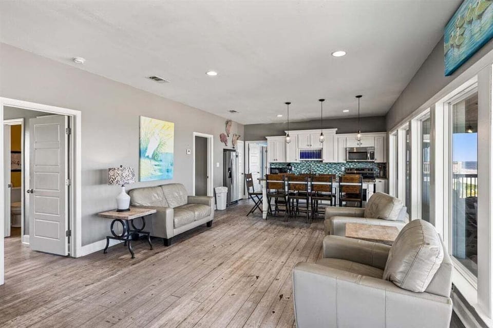 Large coastal living area with open floor plan, stylish furnishings, oversized windows, and seamless indoor-outdoor flow for relaxing beachfront getaways.