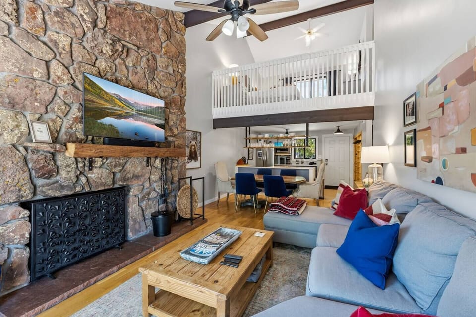 Spacious living room with wood burning fireplace, smart TV, and walkout patio overlooking the golf course