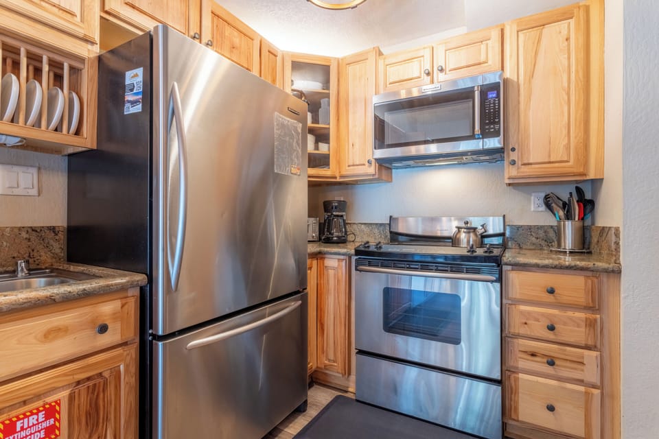 Kitchen w/ solid granite countertops and stainless steel appliances.