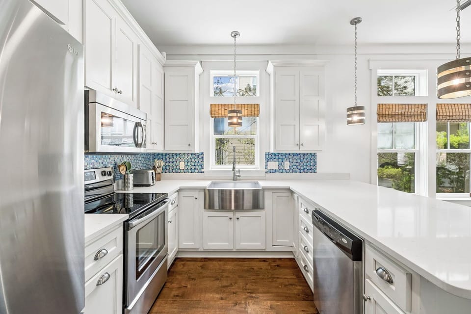 Step into your bright, coastal-inspired kitchen with white cabinetry, ocean-blue tile accents, and modern appliances—perfect for preparing your favorite meals.