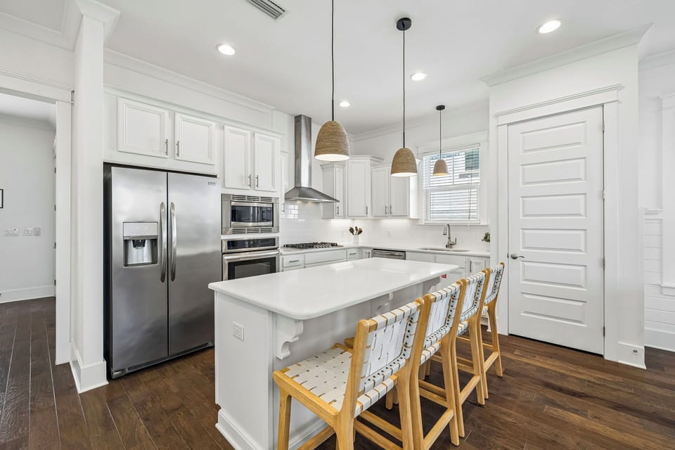 Step into your bright, modern kitchen with crisp white cabinetry, stainless steel appliances, and a spacious island where you can gather for breakfast or unwind with evening cocktails.