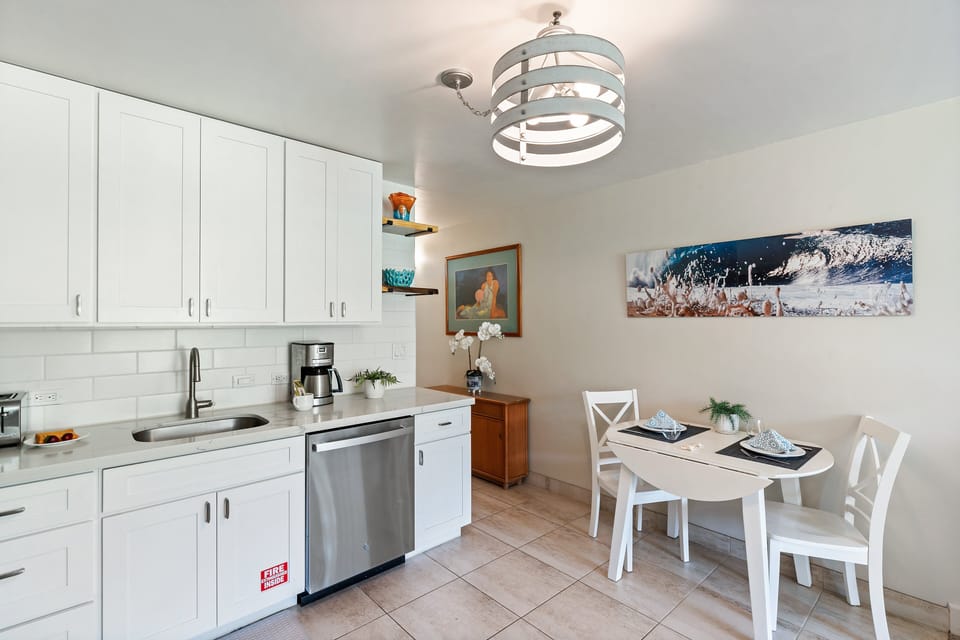 Fully equipped kitchen with clean white cabinetry and a dedicated dining space for two.
