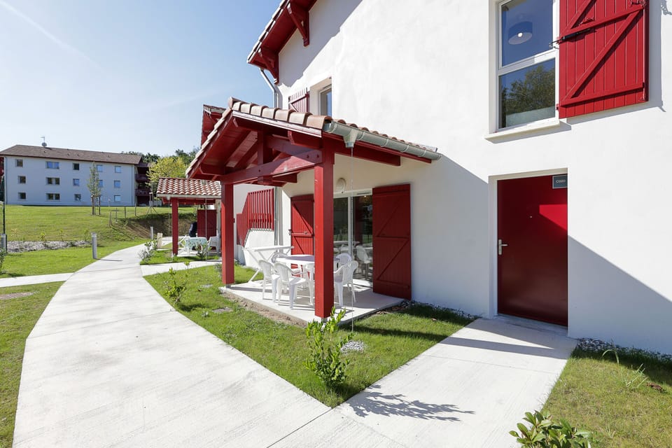 Your home away from home — the signature red-and-white Basque architecture of Le Domaine d'Uhaina, set among well-maintained green surrounds.
