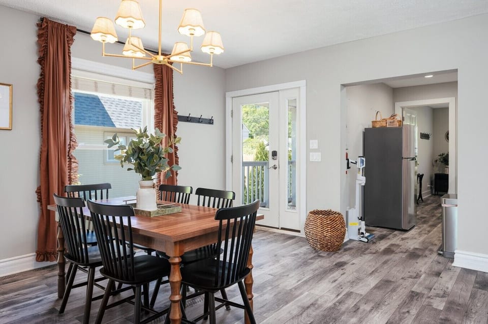 A modern dining space with a wooden table and chairs, connected to a minimalist kitchen. 🍽️