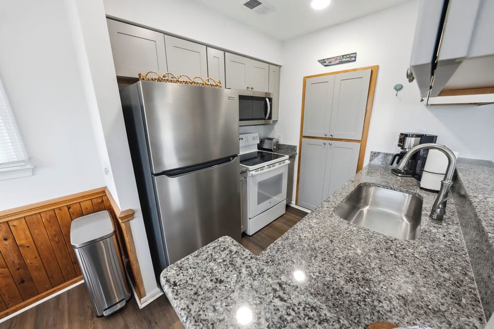 Modern galley kitchen with stainless appliances & granite tops