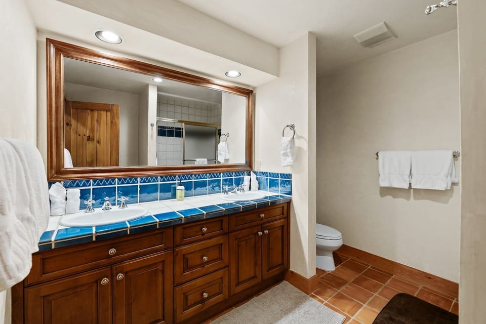 A double vanity with blue tile countertops and framed mirror in the bathroom.