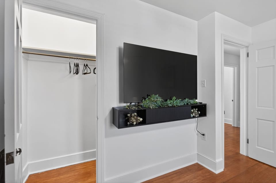 Wall-mounted TV, open closet, and clean modern design