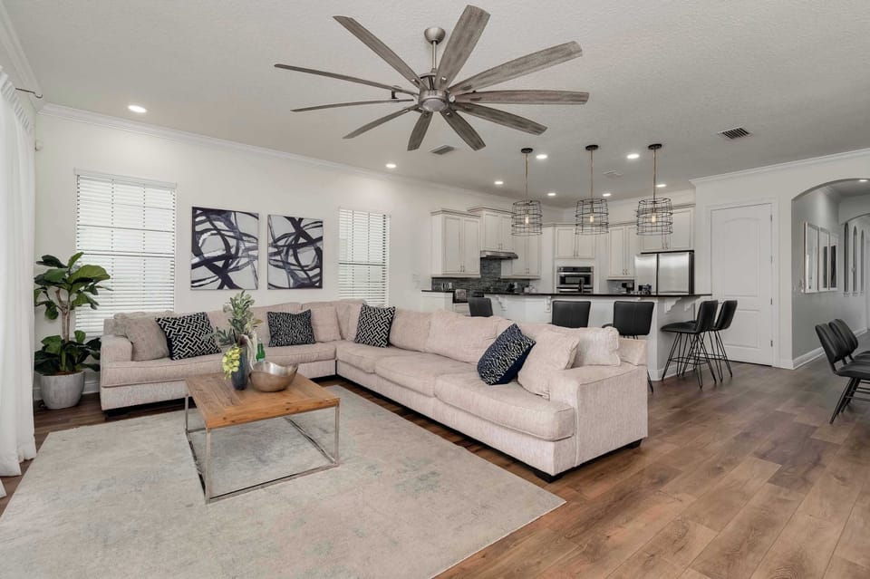 Spacious living area with a large sectional sofa and open kitchen featuring modern lighting.