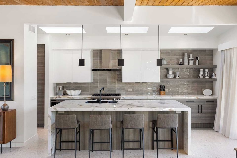 Marble waterfall island with designer bar seating — the centerpiece of this show-stopping kitchen.