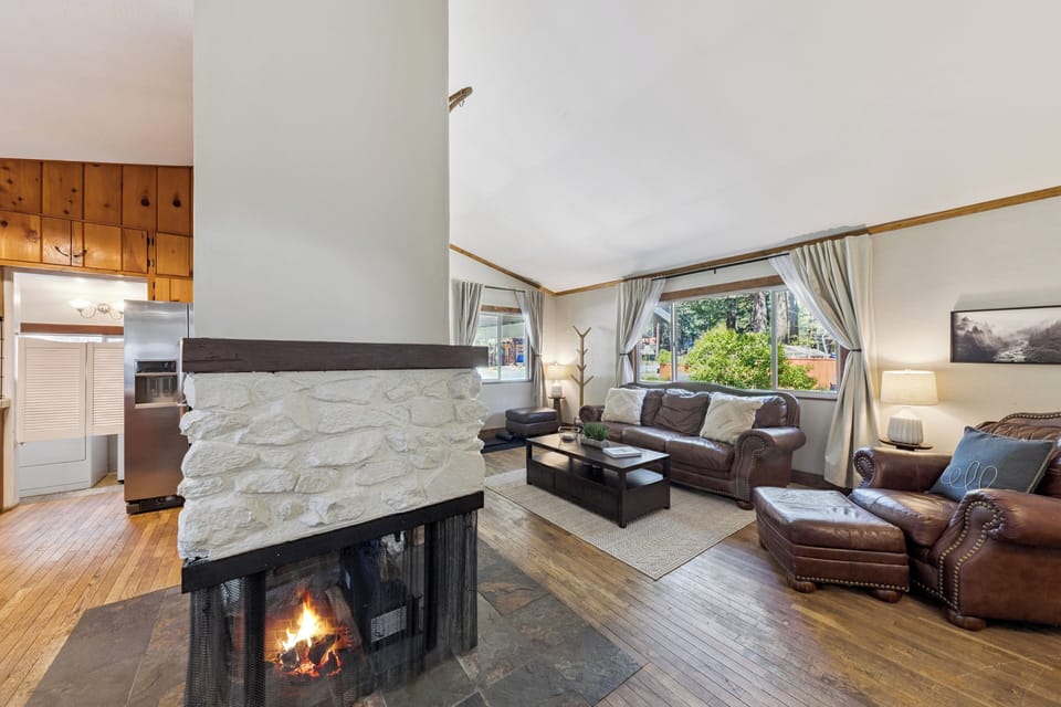 Unwind in this inviting living room where your comfort takes center stage. Sink into plush leather seating by a warming stone fireplace, perfect for cozy evenings after exploring nearby trails.