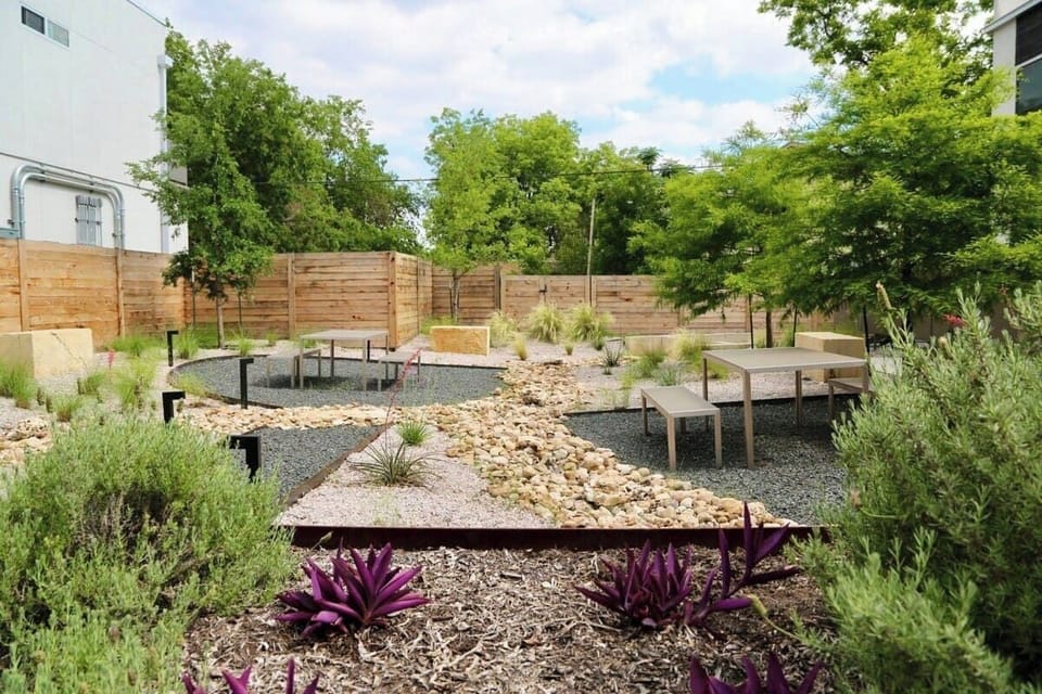 Lush courtyard behind back enclosed patio and features picnic tables.