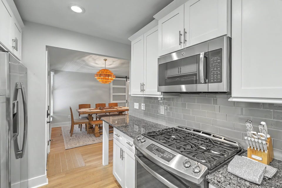 This perspective highlights the kitchen's practical open flow, looking past the stainless steel refrigerator straight into the boho-styled dining room setup.
