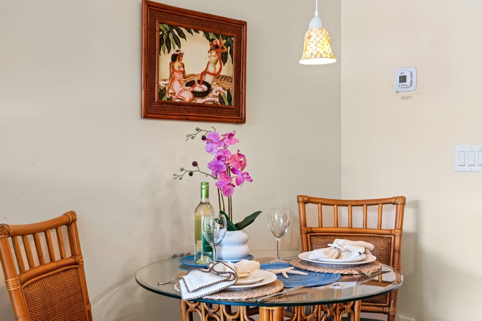 Glass table set for two, wine and orchid glowing under pendant light.