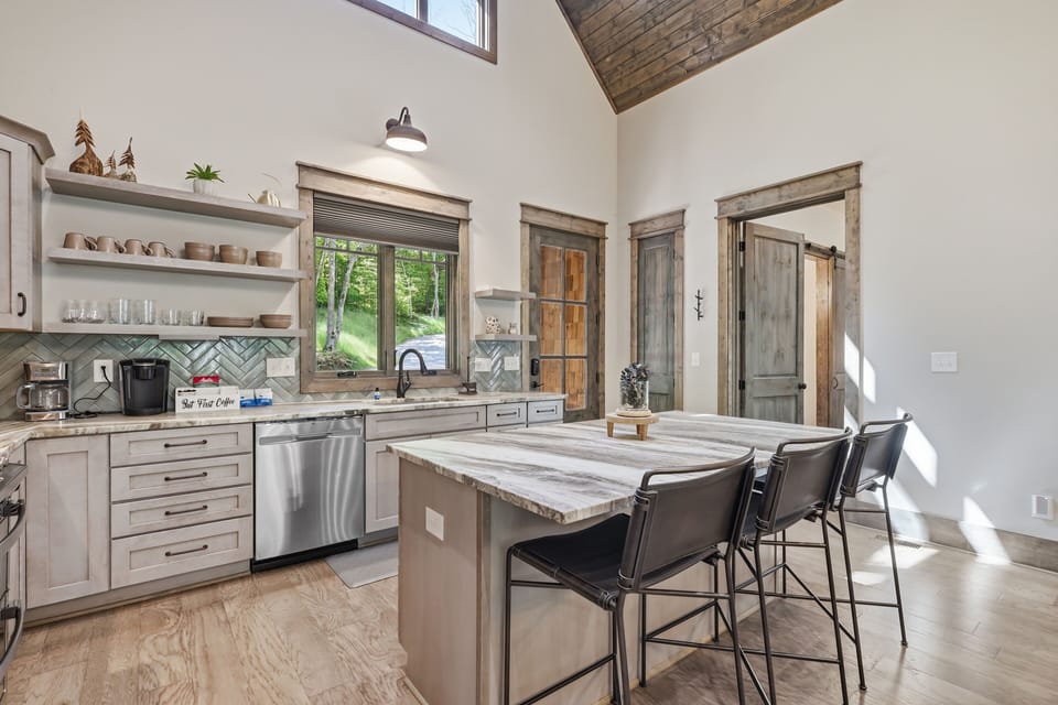 Rustic-modern kitchen featuring vaulted ceilings, island seating, and a bright, open feel — a stylish and inviting space for cooking, gathering, and enjoying meals together.