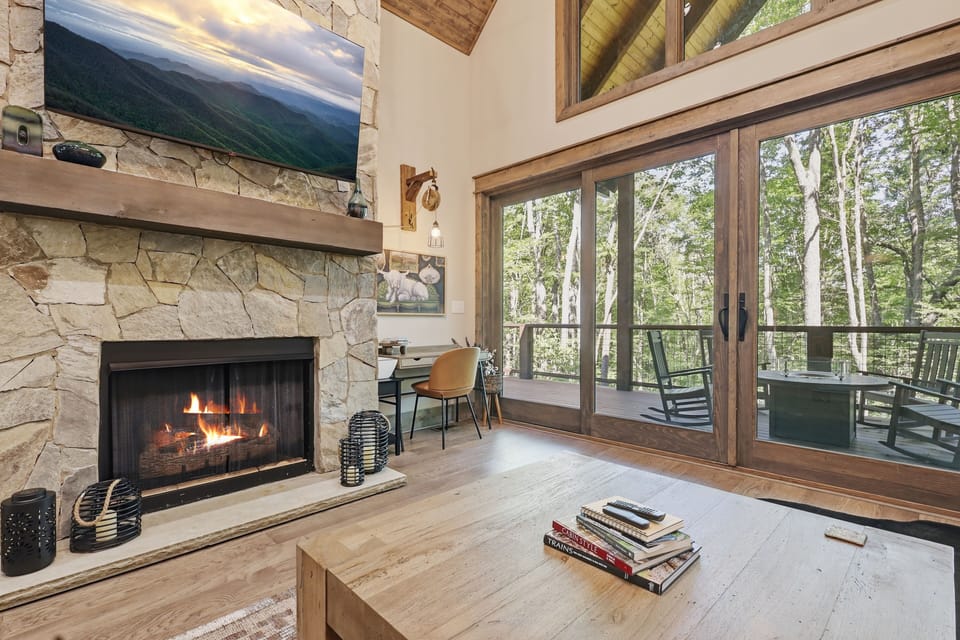 Cozy stone fireplace and treehouse-style deck featuring serene forest views — a magical combination perfect for relaxing indoors or stepping outside to soak in the peaceful mountain surroundings.