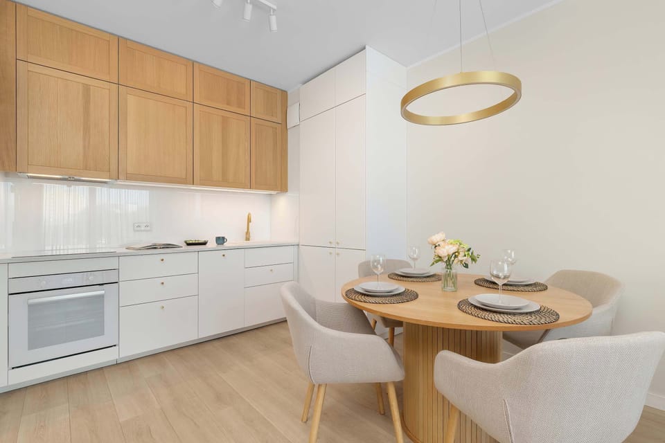 A stylish kitchenette with wooden cabinets, a dining area, and modern lighting.