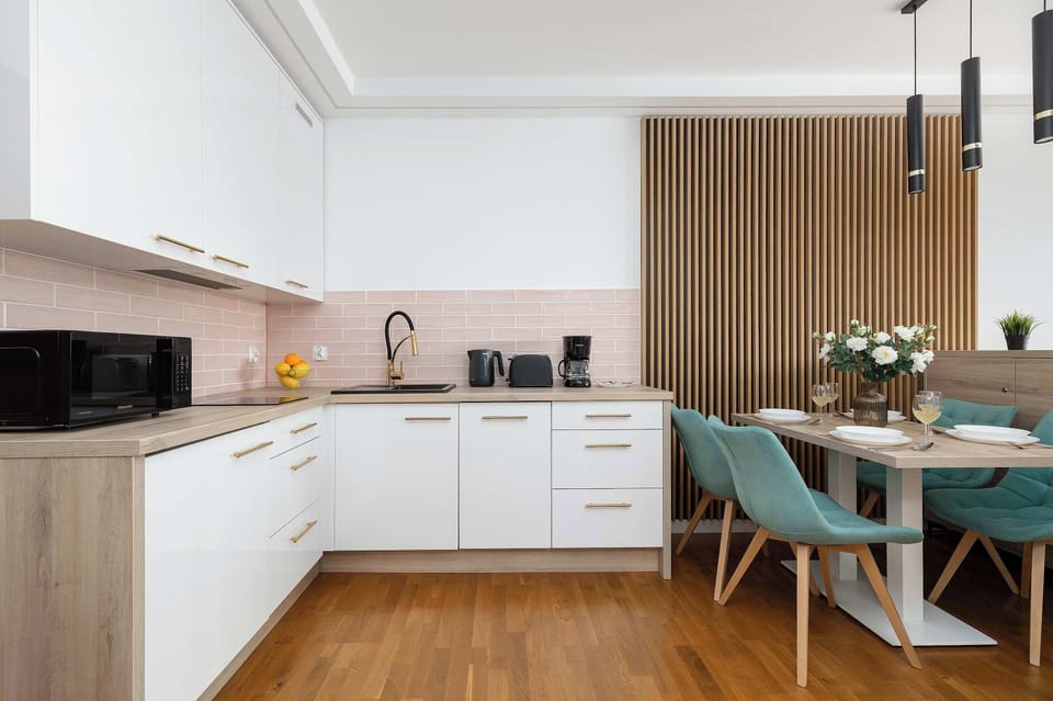 A dining area connected to the kitchen with a wooden table and turquoise upholstered chairs. The setting feels cozy and designed for shared meals.