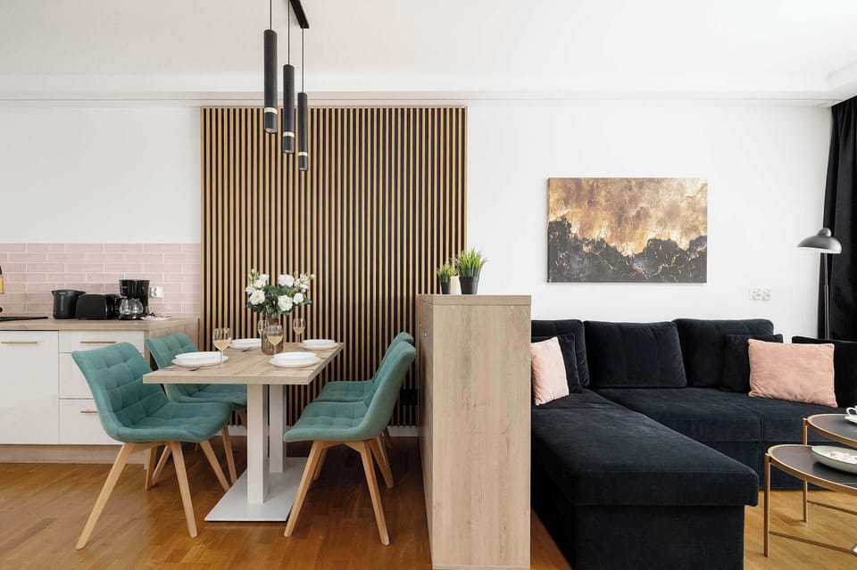A living room with a dark sofa and a TV mounted on a wooden media wall. The room appears modern and comfortable for relaxation.
