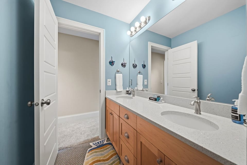 A calm, coastal-inspired bathroom awaits you with twin sinks and ample counter space—perfect for fresh mornings and relaxing evenings during your stay.