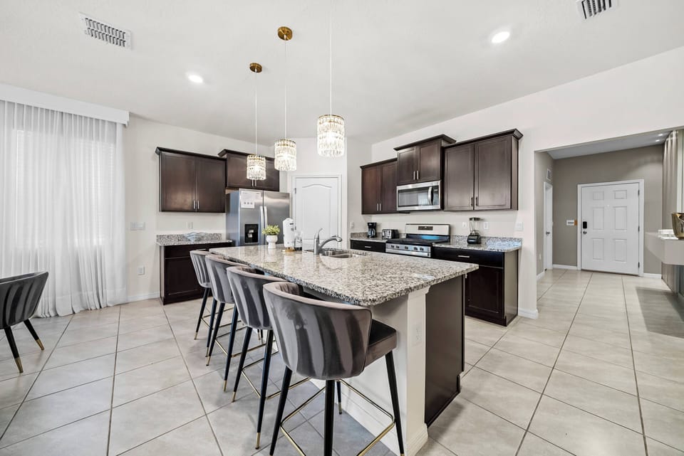 Savor delicious meals in our chic kitchen with elegant wooden cabinetry and sleek granite countertops. The spacious island and modern bar stools create a casual dining experience in a warm, inviting space full of natural light.
