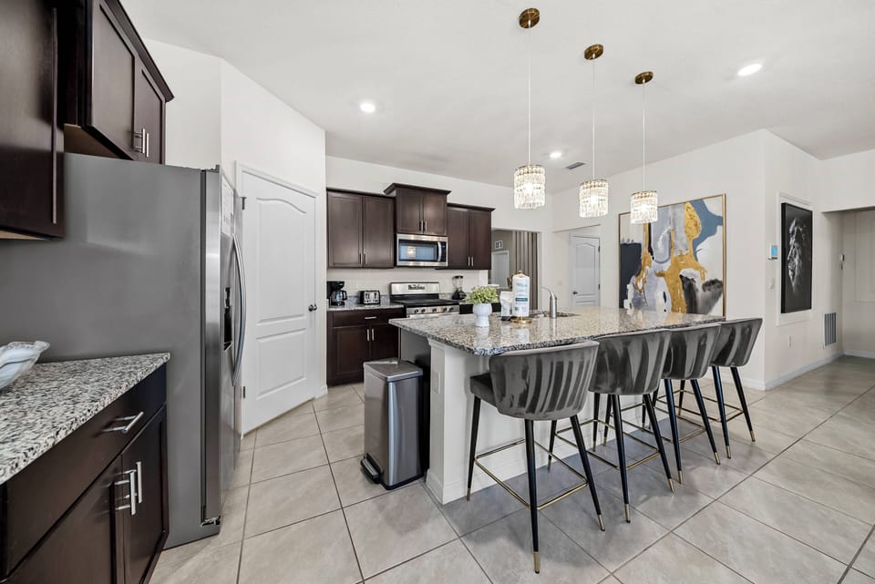 Experience a stylish kitchen with dark cabinets and elegant granite countertops. The cozy island with modern bar stools is perfect for casual dining, while bright pendant lights add a warm and inviting touch.