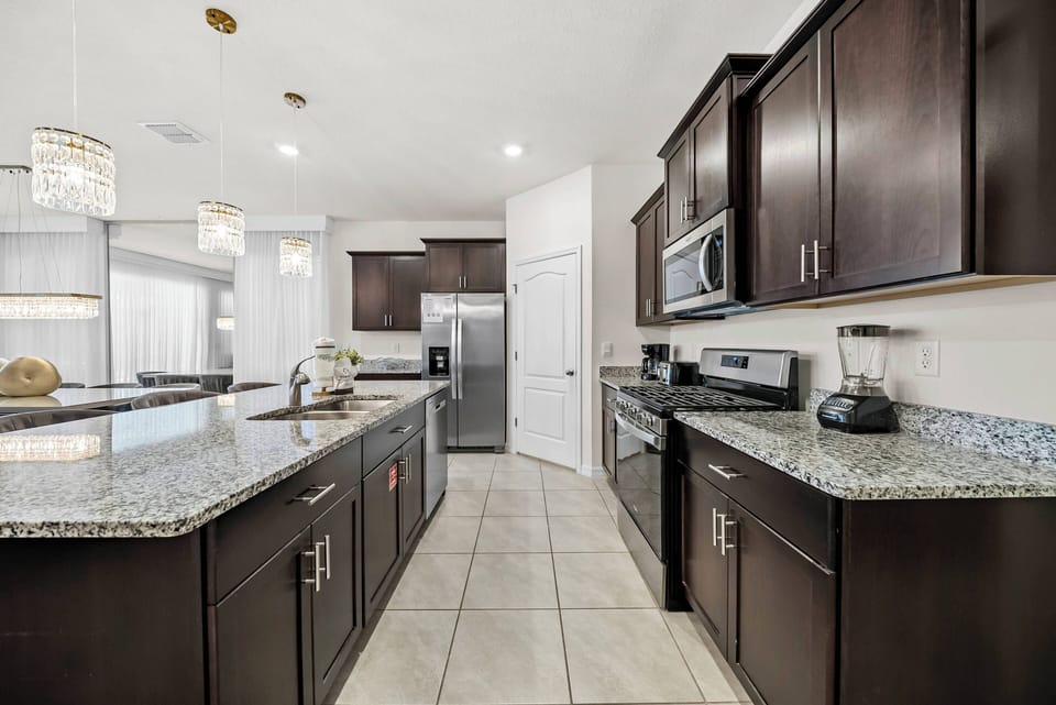 Discover this beautifully designed kitchen with rich dark cabinetry and elegant granite countertops, perfect for culinary adventures. The spacious layout and natural light from large windows create a welcoming atmosphere.