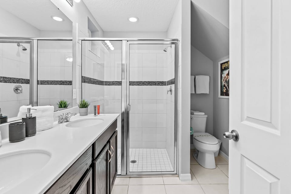 Experience the bright bathroom with sleek glass shower doors and chic black accents that foster a refreshing atmosphere. The modern vanity and smooth tile flooring create an inviting space to relax after a day of adventure.