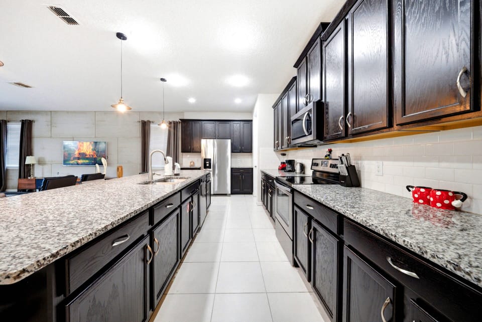 This spacious kitchen showcases sleek black cabinetry and beautiful granite countertops, inspiring your culinary creativity. Its bright, airy design and modern lighting seamlessly connect to the living area, making it ideal for.